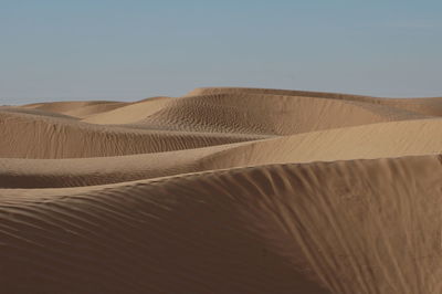 Sand dune in desert against clear sky