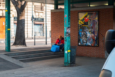 People sitting on sidewalk by building