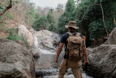 Full length of man standing by rocks in forest