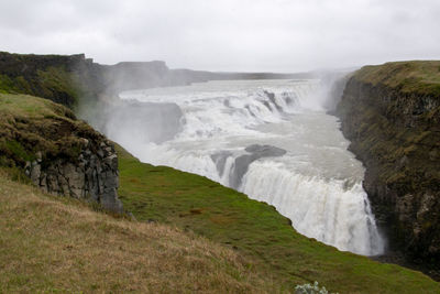 Scenic view of waterfall against sky