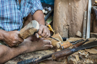 Midsection of man cutting wood