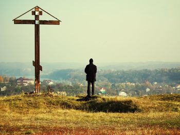 Rear view of man standing on field against clear sky