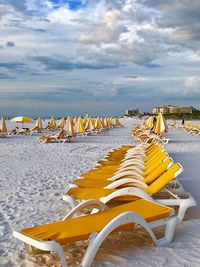 Deck chairs on beach against sky