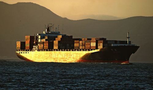 Ship sailing on sea against sky during sunset