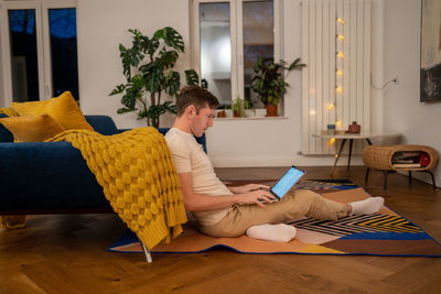 Serious man workaholic freelancer working on laptop in dark at home looking at screen.