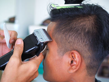 Cropped hands of hairdresser cutting man hair