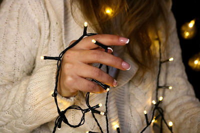 Midsection of woman holding illuminated string lights