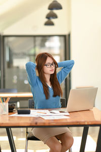 Young woman using laptop while sitting on table
