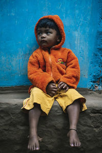 Full length of boy sitting against wall