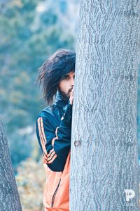 Young woman looking at tree trunk