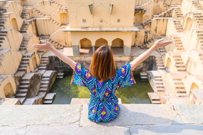 Rear view of woman standing with arms raised