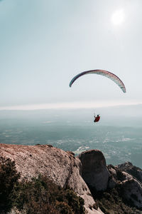 Person paragliding over sea against sky