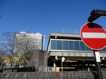 Low angle view of road sign against clear blue sky