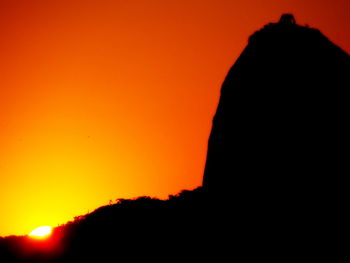 Silhouette mountains against orange sky