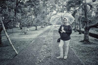 Full length portrait of smiling woman standing on land