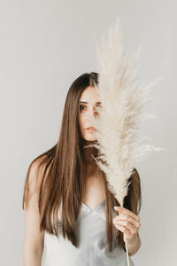 Portrait of young woman holding feather