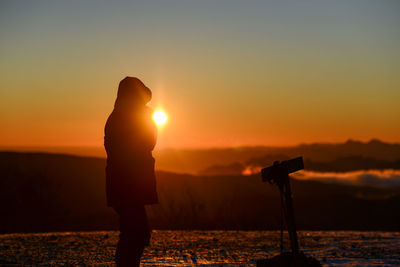 Silhouette woman standing at beach during sunset