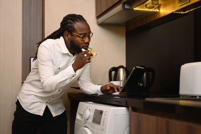 Side view of young man drinking coffee at home