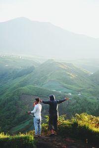 Rear view of people standing on mountain against clear sky