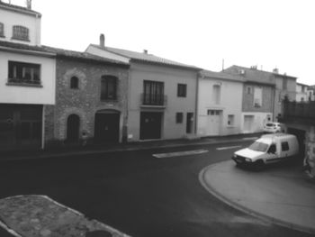 Cars on street by buildings against sky