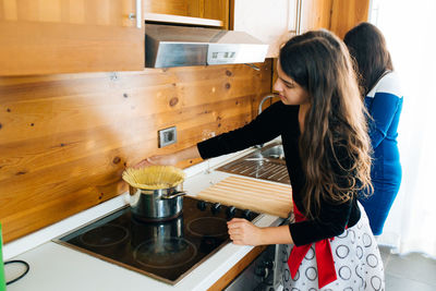 Daughter preparing food and mother standing in kitchen at home