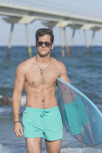 Shirtless man with surfboard at beach