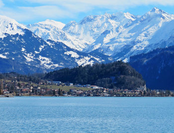 Scenic view of sea by mountain against sky