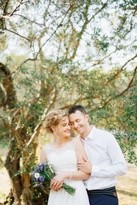 Couple embracing while holding bouquet outdoors