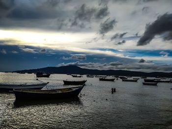 Boats moored in sea against sky at dusk