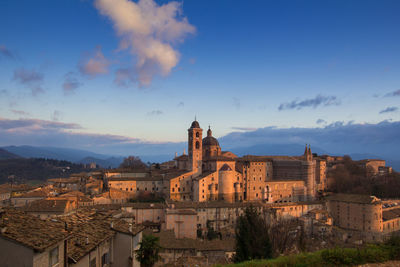 Buildings in town against cloudy sky