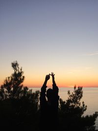Silhouette woman against sea during sunset