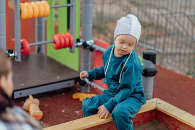 A boy, person with down syndrome walks in the park with his mother