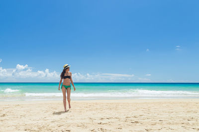 Rear view of woman standing at beach against sky