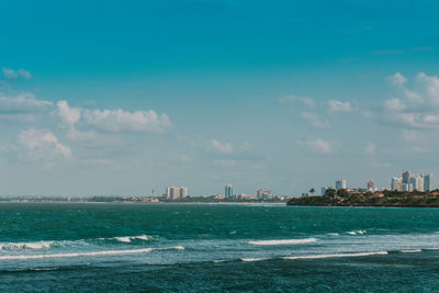 Scenic view of sea by buildings against sky