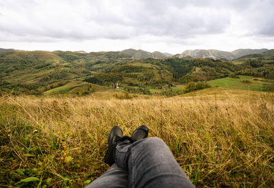 Low section of woman on land against mountains and sky