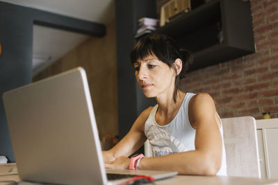 Contemplating woman using laptop at home