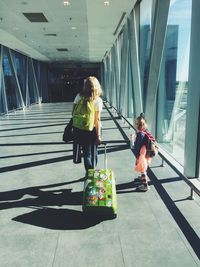 Rear view of mother with daughter walking on elevated walkway