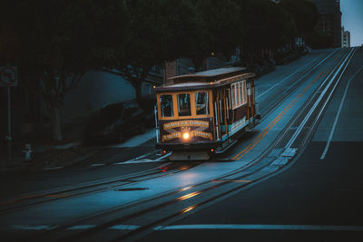 Illuminated railroad tracks by road at night