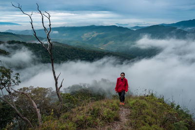 Rear view of woman standing on mountain against sky