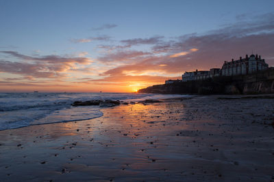 Surf on beach against cloudy sky at dusk