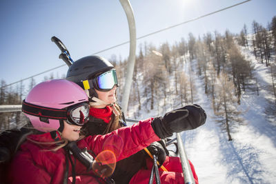 Mother and daughter enjoying while traveling in ski lift