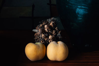 Close-up of peaches by dried roses on table