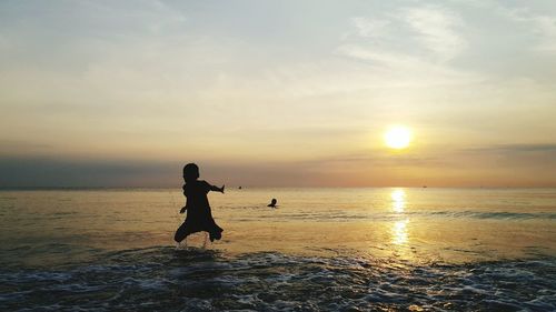 Silhouette man on beach against sky during sunset