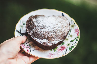 Cropped image of hand holding plate with cake