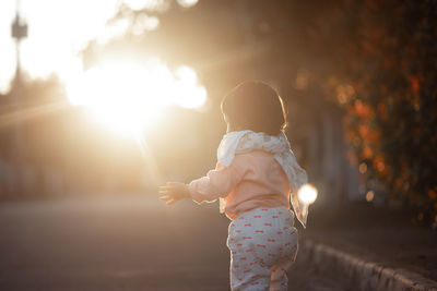 Rear view of girl standing on land during sunset