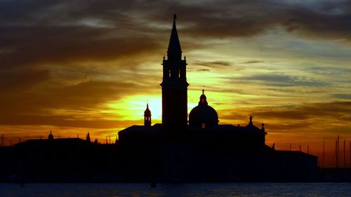 Silhouette of building against cloudy sky during sunset