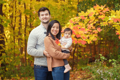 Portrait of smiling family standing at park during autumn