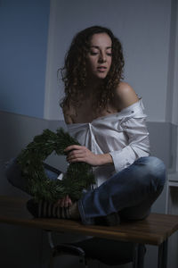 Woman looking away while sitting on potted plant