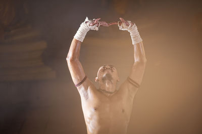 Close-up of shirtless kick boxer gesturing during competition