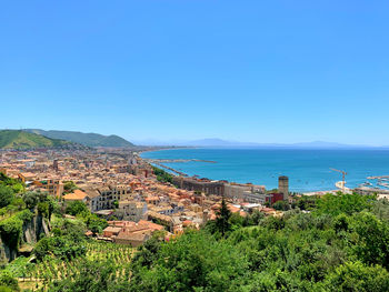 Townscape by sea against clear blue sky